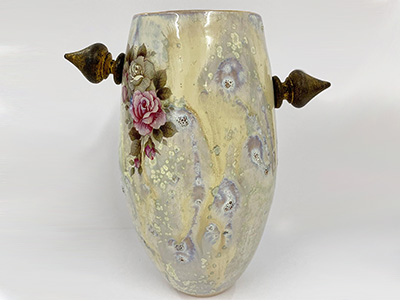 An ornate yellow vase covered with rose decals