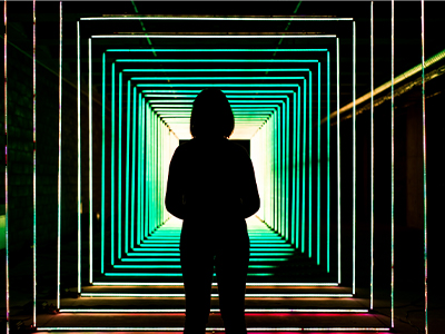 An image of a girl looking down a tunnel, lit green
