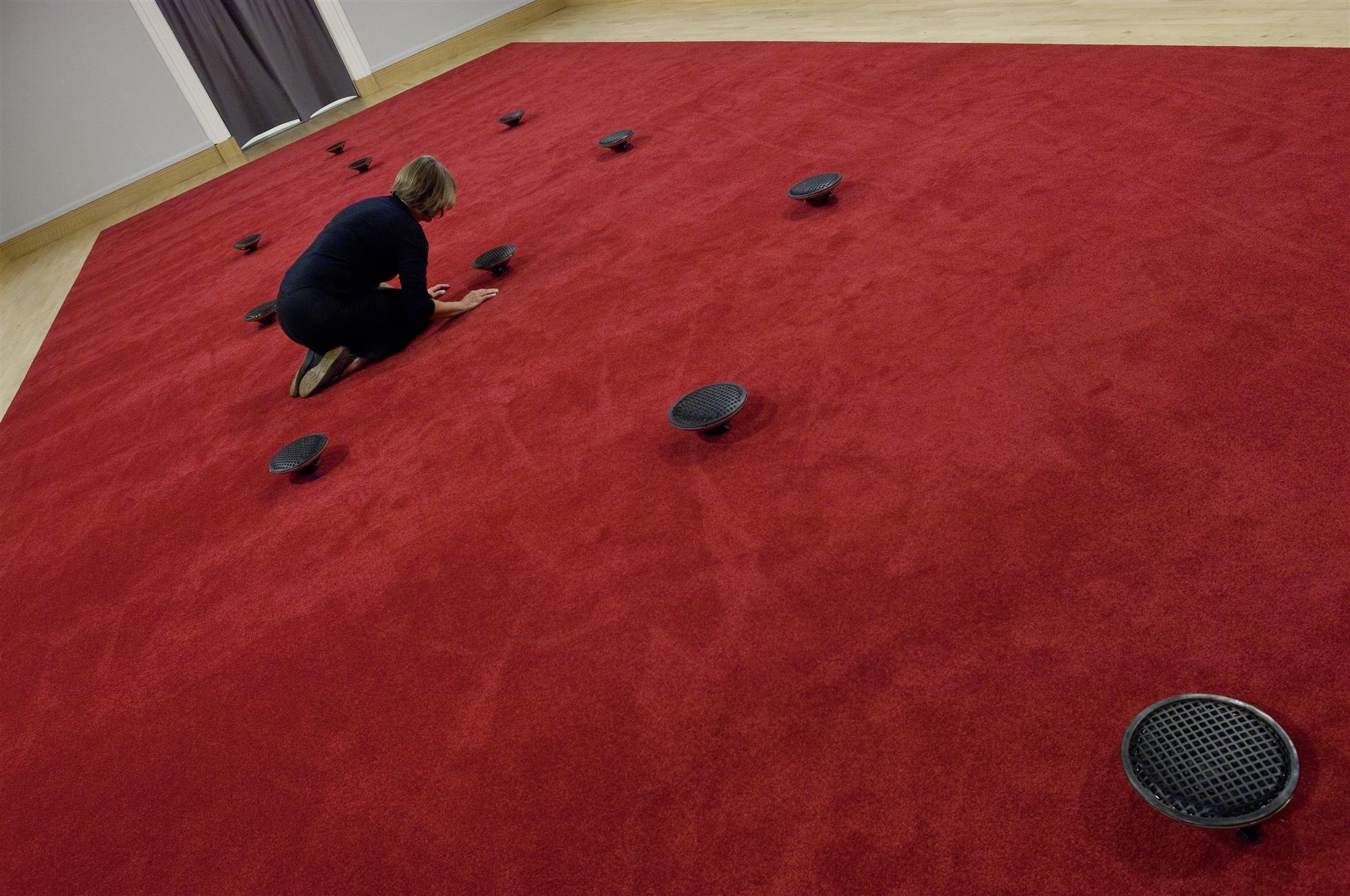 a photo of James Webb Prayer installatino in the Djanogly Gallery: a red carpet with 12 floor based speakers
