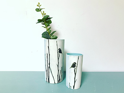 Long vases with black trees and birds painted on them