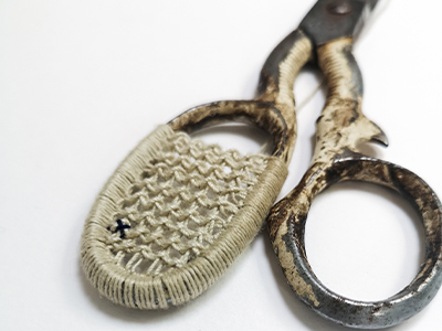 Metal scissors with knitting between the handles