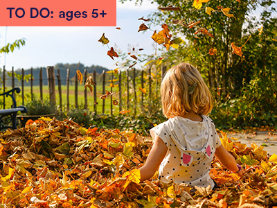 Young girl plays in pile of gold leaves with park backdrop. Keywords in corner: TO DO: ages 5+