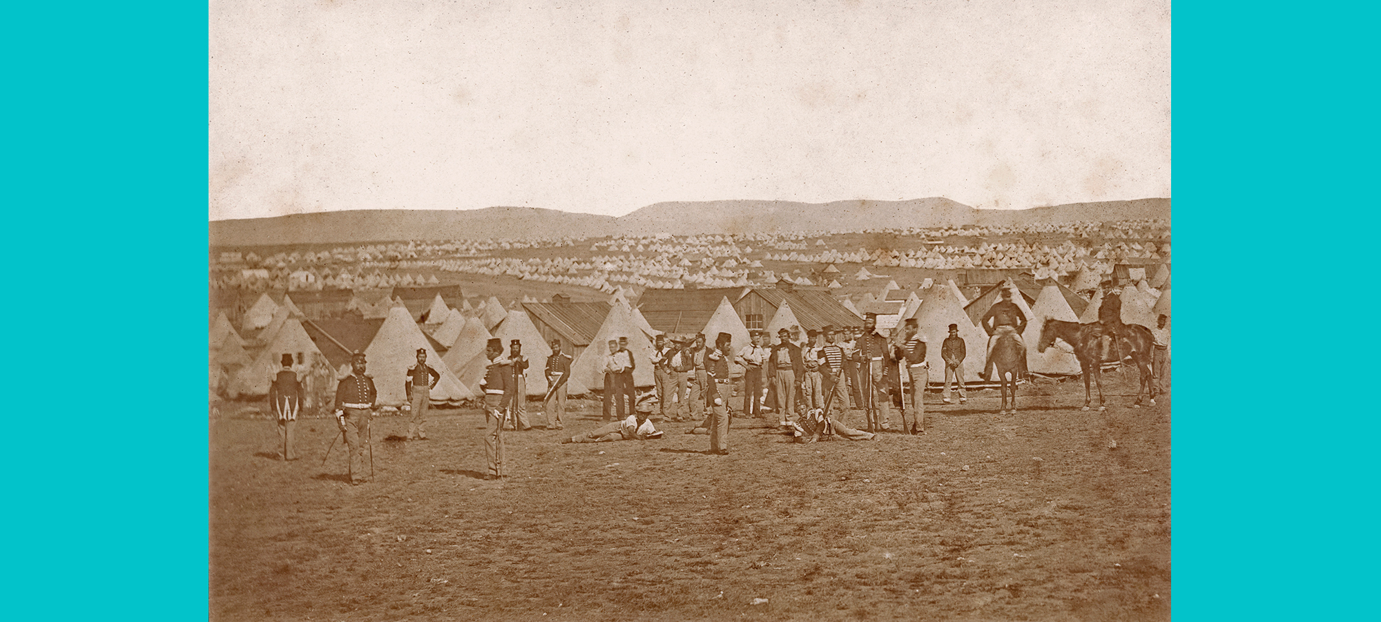 photograph taken of men at a camp standing in soldier uniform in front of tents