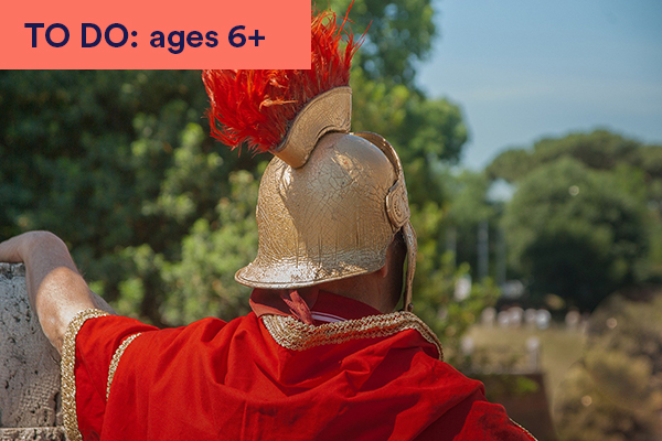 Photo of the back of a man dressed as a roman soldier wearing gold armour and helmet with red feathers. Keywords in corner: TO DO: ages 6+