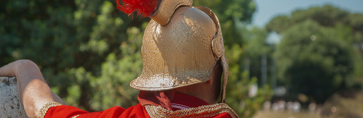 Photograph of the back of the man dressed as a Roman soldier with red cape and gold helmet with red feathers